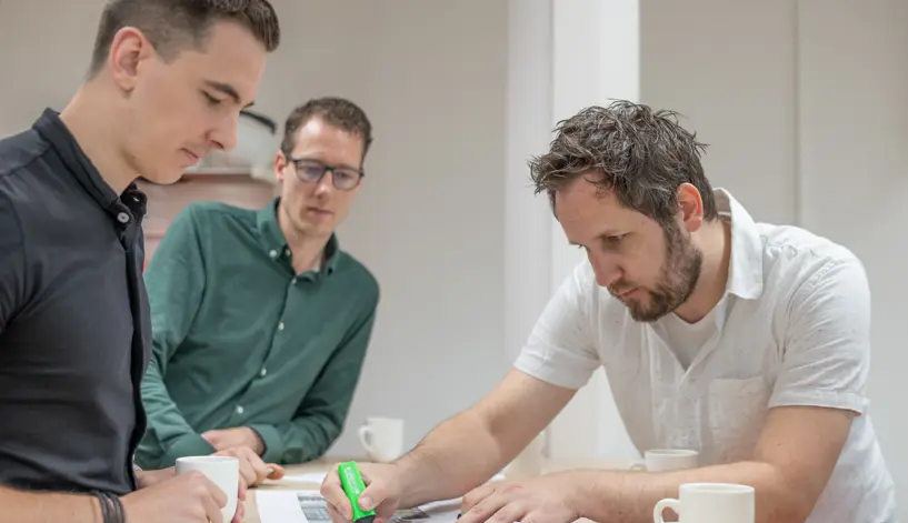 Collega's Vanderkamp staan rond tekentafel