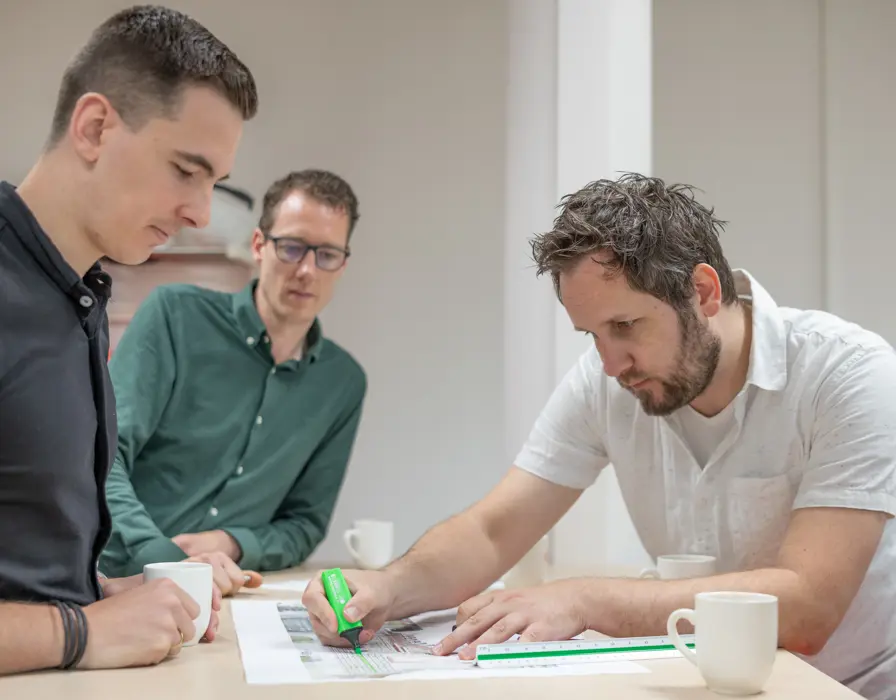 Collega's Vanderkamp staan rond tekentafel